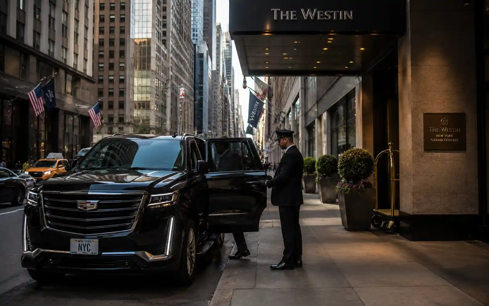 Chauffeur holding open the rear door of a luxury SUV outside a Midtown Manhattan hotel
