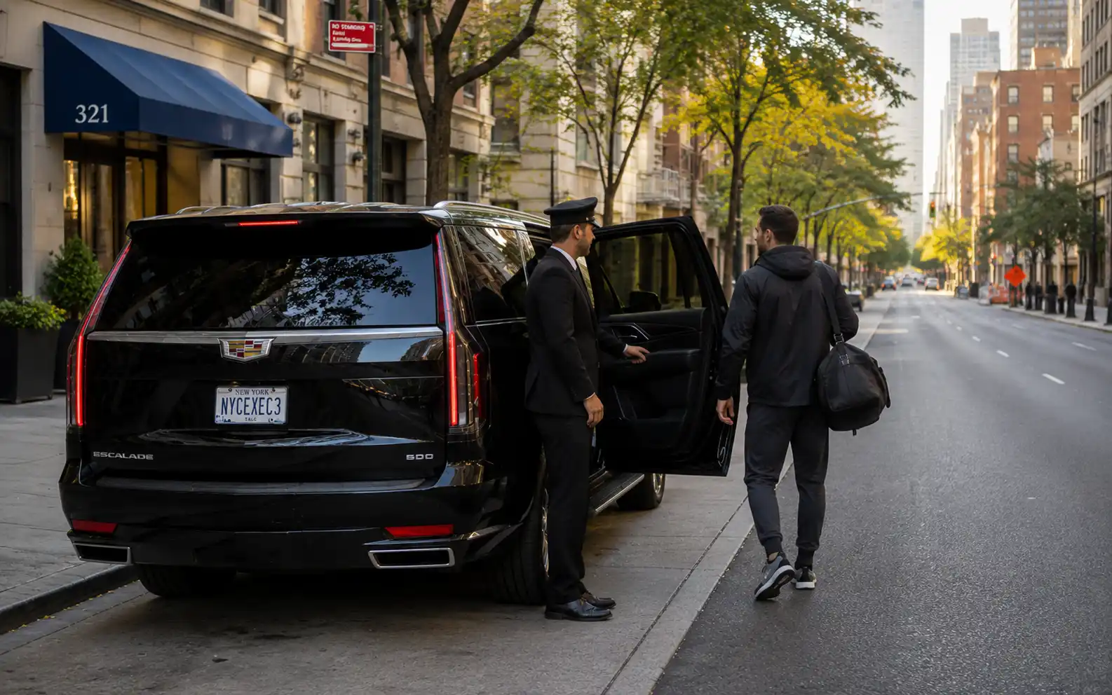 Chauffeur holding open the rear door of a car for a passenger in sports clothing
